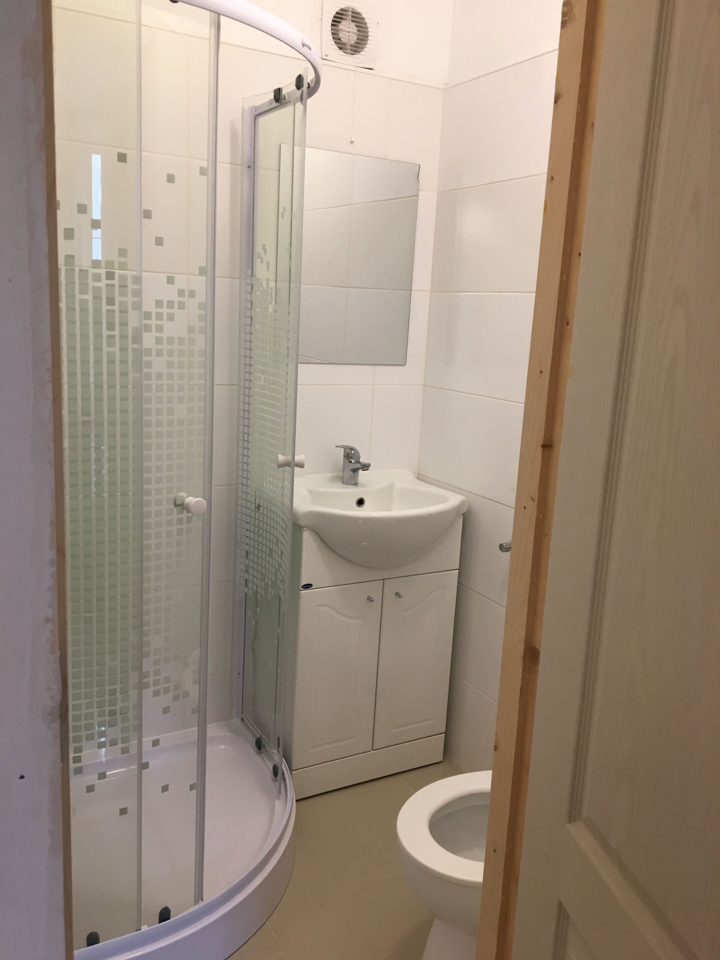 A bathroom with a glass shower enclosure, a sink, and a toilet.