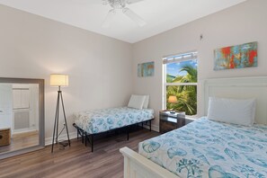 A bedroom with two single beds, a standing lamp, a window with a view of palm trees, and artwork on the walls. - 🌴Private Screened Pool Home | Walk to Ft Myers Beach | Palm Island🌴 (Fort Myers Beach)