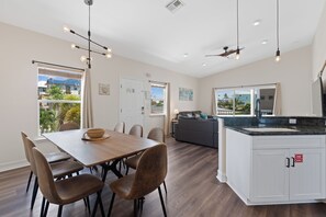 A modern kitchen with a dining area, wooden flooring, and a view of the outside. - 🌴Private Screened Pool Home | Walk to Ft Myers Beach | Palm Island🌴 (Fort Myers Beach)