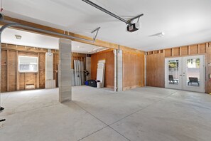 A spacious indoor area with exposed wooden beams, a concrete floor, and a door leading to an outdoor area. - 🌴Private Screened Pool Home | Walk to Ft Myers Beach | Palm Island🌴 (Fort Myers Beach)