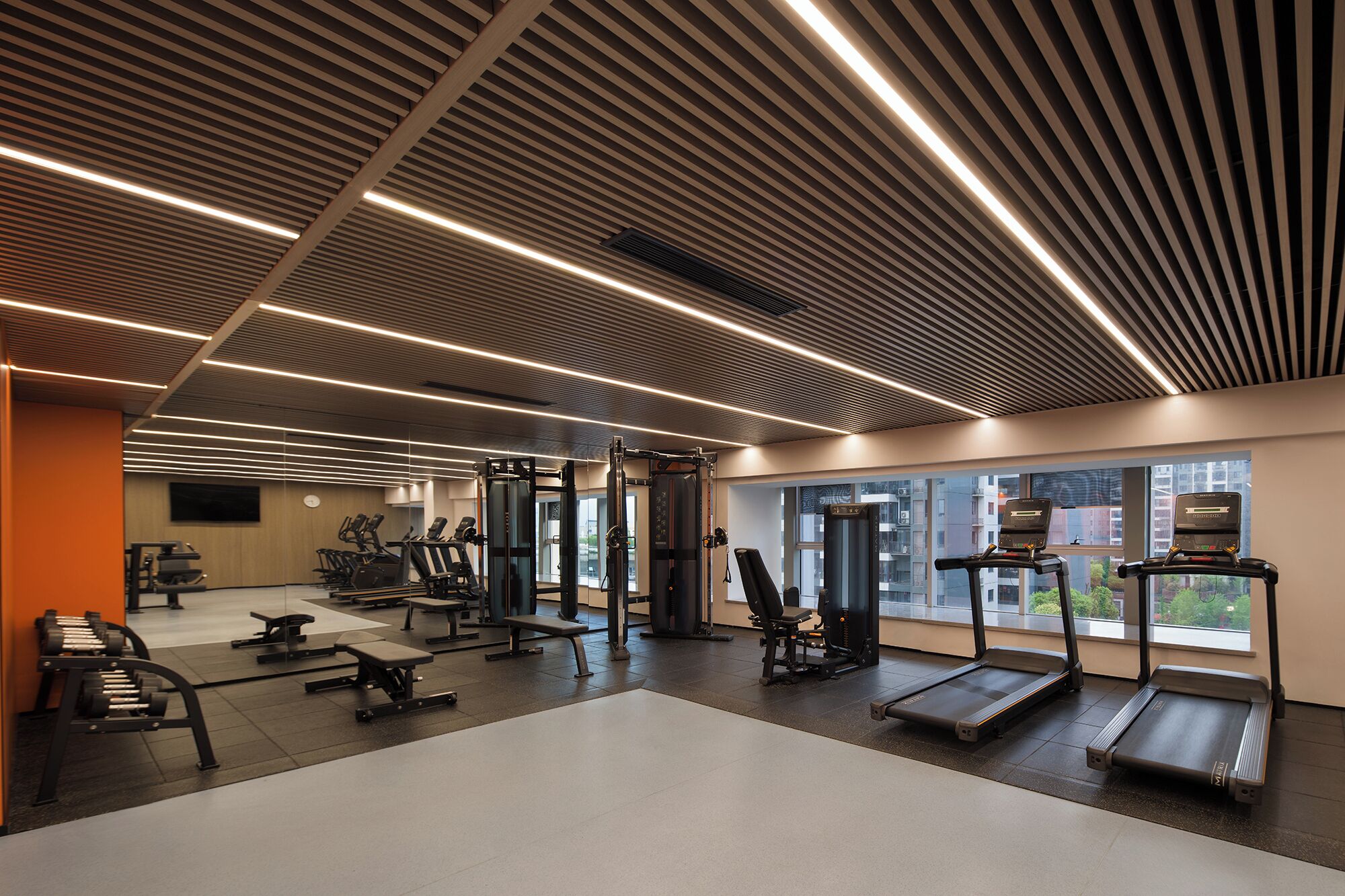 A modern gym with treadmills, weight machines, and benches.