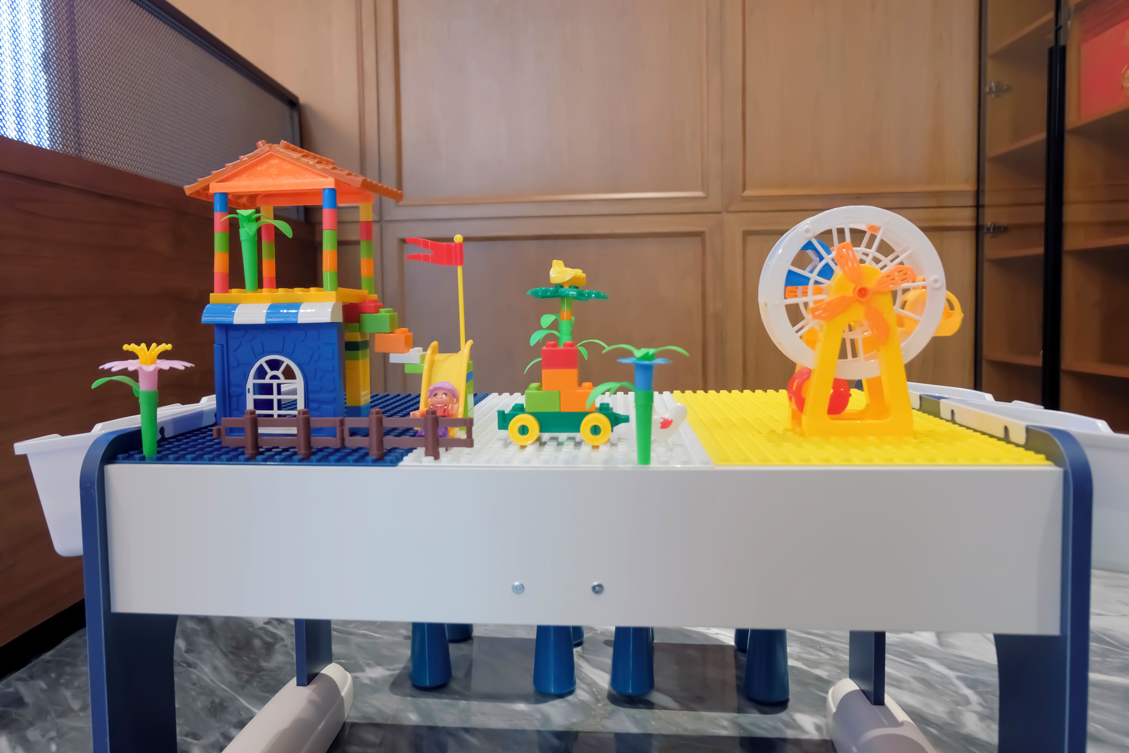 Un set de LEGO con una casa pequeña, un coche, un molino y una jirafa.