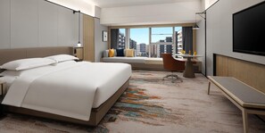Une chambre d’hôtel avec un grand lit, un bureau, une télévision et une fenêtre donnant sur la ville.