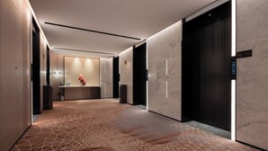 En modern hotellobby med ett marmorgolv, en receptionsdisk och en stor hiss.
