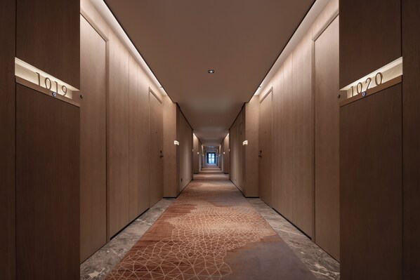 A long, narrow hallway with wooden walls and numbered doors, leading to a bright end. - voco Changsha Airport by IHG (Changsha)