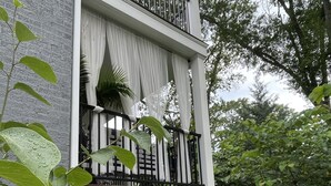Un balcon doté d’une balustrade blanche, d’un panneau en treillis blanc et d’un rideau blanc.