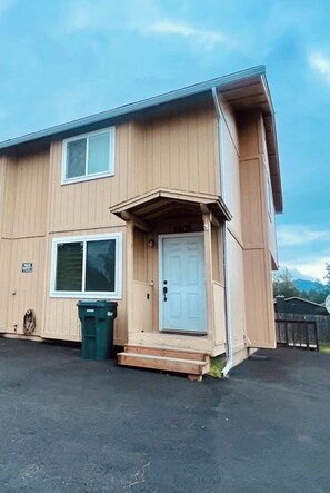 A two-story building with a front door, a window, and a trash bin. - Rustic-modern style Alaskan retreat (Anchorage)