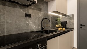 A modern kitchen with a black countertop, stainless steel sink, and a built-in oven. - La Maison Suite   Suite 2 (Zakynthos)