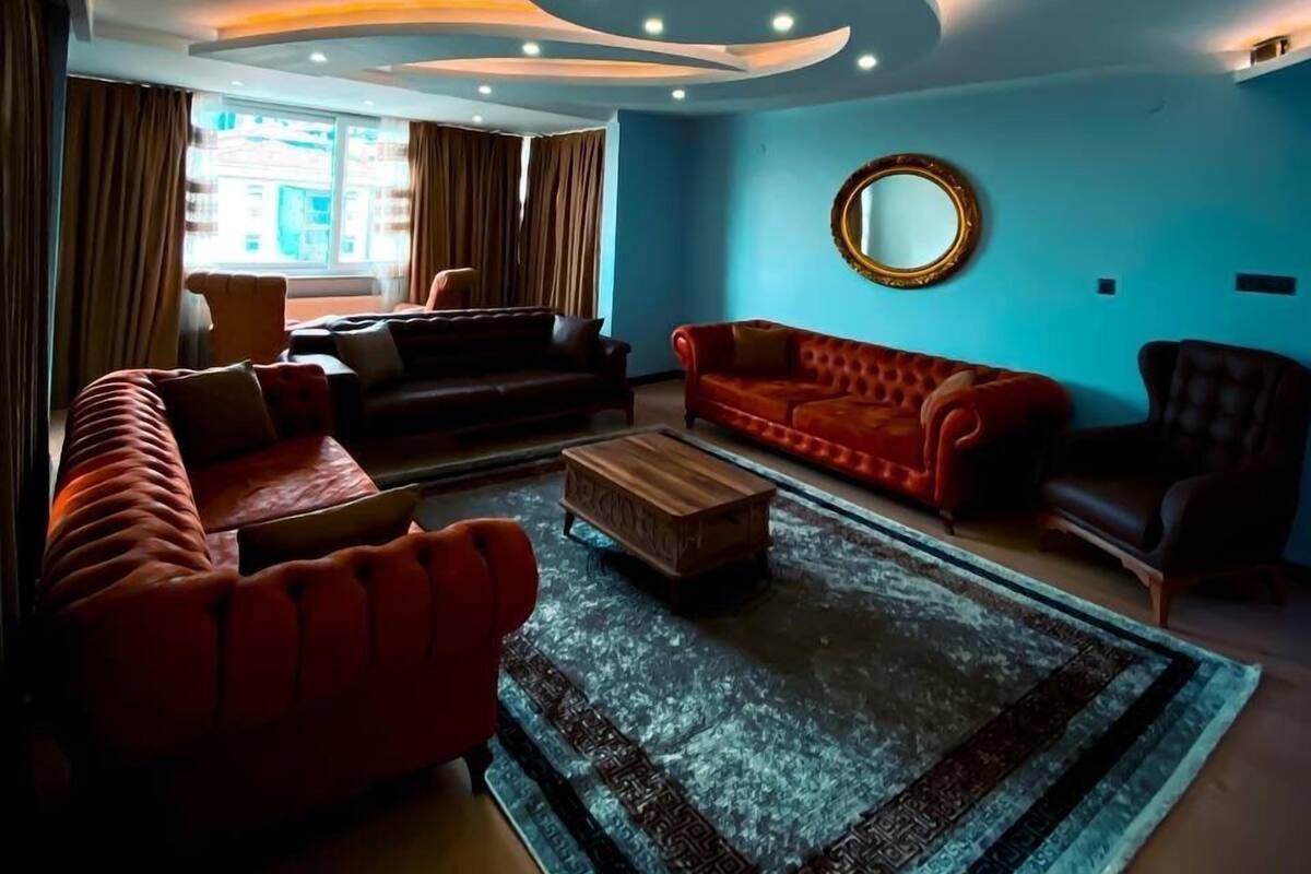 A modern living room with a blue accent wall, a round mirror, and a red sofa.