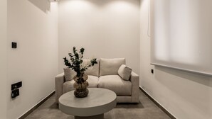 A modern, minimalist room with a beige sofa, a round coffee table, and a vase with flowers. - La Maison Suites   Studio 3 (Zakynthos)