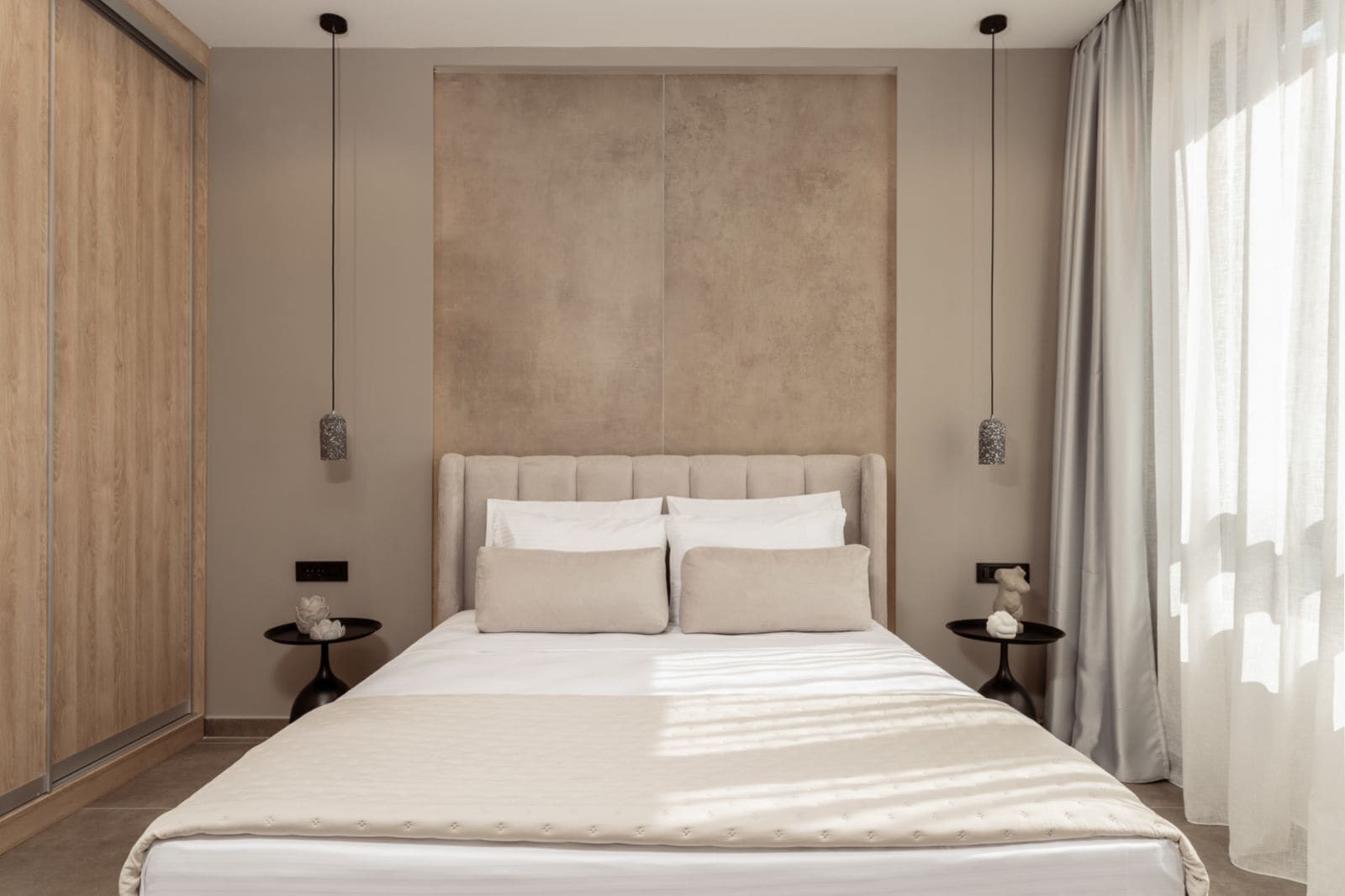 A modern bedroom with a large bed, two bedside tables, and a neutral color scheme.