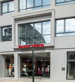 Un edificio moderno con un amplio ventanal y un cartel que dice "TALY WEILL".