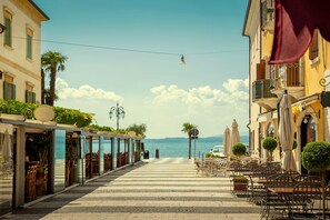 A seaside promenade with outdoor seating, a view of the sea, and buildings with balconies.