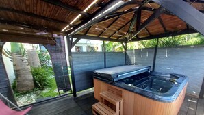 Un jacuzzi bajo una pérgola de madera con vistas a un jardín.