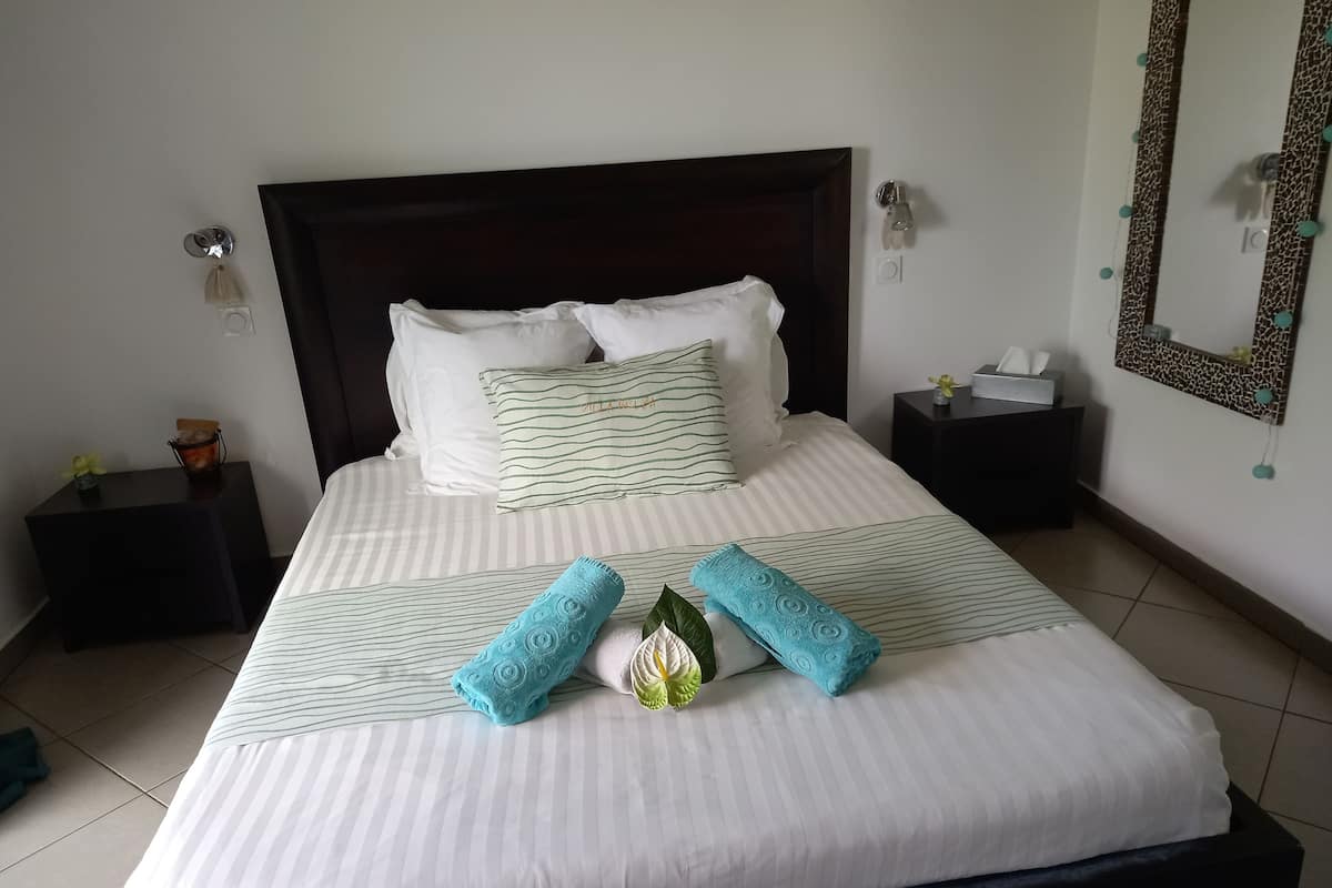 A neatly made bed with striped bedding, two blue towels, and a decorative pillow.