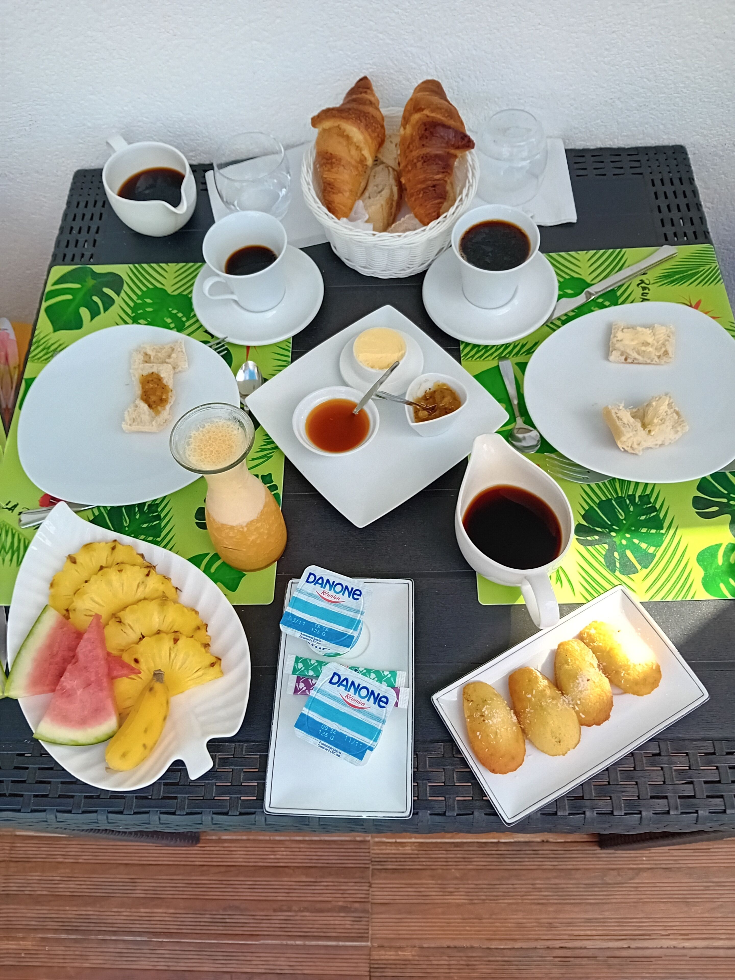 A breakfast buffet with croissants, coffee, fruit, and Danone yogurt.