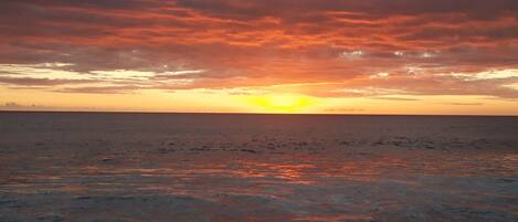 Ein Sonnenuntergang über ruhigem Meer mit klarem Horizont.