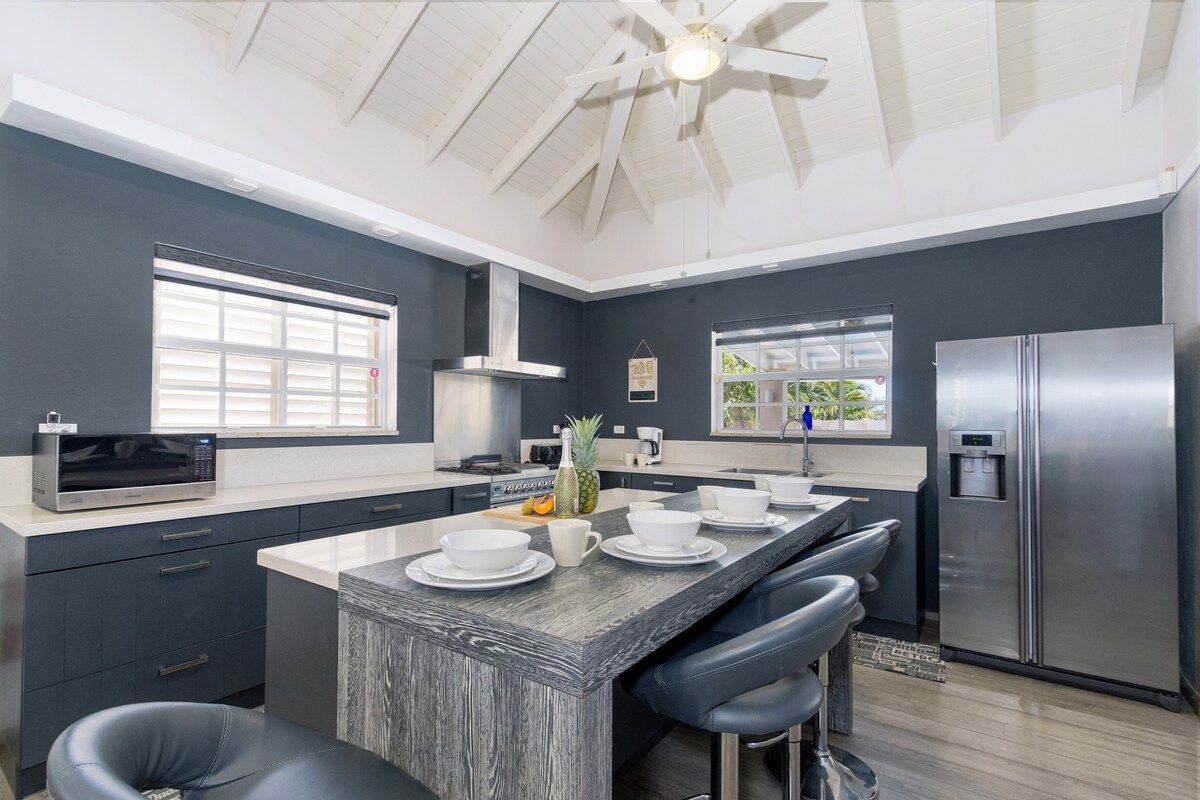 A modern kitchen with a central island, stainless steel appliances, and a ceiling fan.