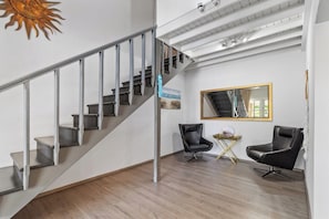 Ein modernes Interieur mit einer Treppe, zwei schwarzen Ledersesseln, einem Spiegel und einer Sonnendekoration an der Wand.