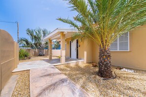 A house with a covered patio, palm trees, and a gravel driveway. - Private Pool Oasis 4BR Home Near Palm Beach, Aruba (Noord)