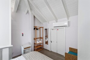 A bedroom with a bed, a wooden shelf unit, a white wardrobe, and an air conditioning unit. - Private Pool Oasis 4BR Home Near Palm Beach, Aruba (Noord)