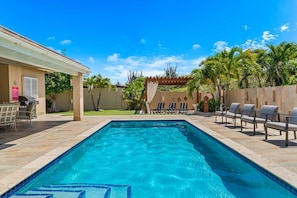 Une piscine avec des chaises longues et un espace patio.