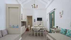Un espai vital compacte amb cuina americana, zona de dinar i saló amb sofà i llit.