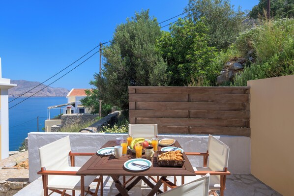 Una mesa preparada con alimentos para el desayuno, con vistas a un paisaje costero.