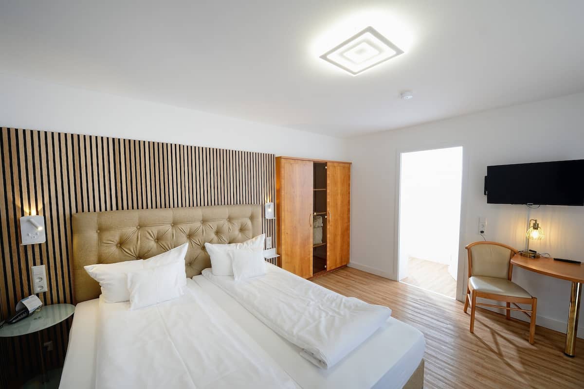 A hotel room with a bed, a TV, a desk, and a wardrobe.