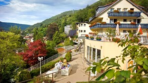 A hotel with a balcony, outdoor seating, and a view of the surrounding greenery and hills. - Wellnesshotel Rothfuss mit Spa und 2 Schwimmbädern (Bad Wildbad)