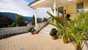 A hotel with a covered outdoor area, steps leading to a balcony, and potted plants. - Wellnesshotel Rothfuss mit Spa und 2 Schwimmbädern (Bad Wildbad)