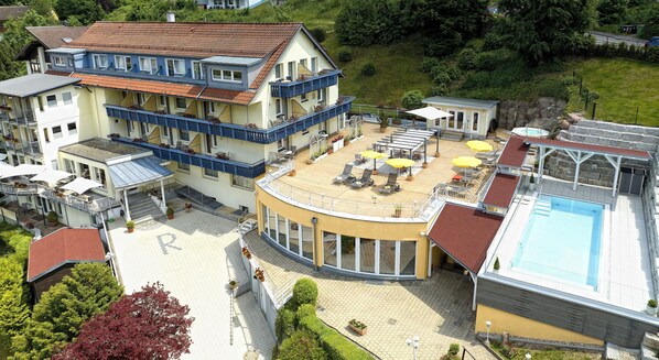 A hotel with a pool, outdoor seating, and a covered deck.
