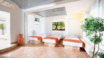 A room with three beds, a large window, and a potted plant.