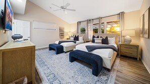 A modern bedroom with two beds, a ceiling fan, a TV, and a large window with curtains. - Sunlit La Jolla Village Gem with Peak Ocean Views! (San Diego)