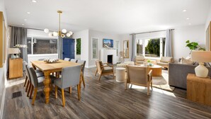 Amplia sala de estar con una mesa de comedor de madera, asientos cómodos y grandes ventanas que ofrecen vistas al exterior.