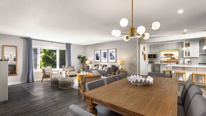 Un salón moderno con una mesa de comedor de madera, sillas tapizadas en gris y una araña.