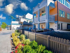 A two-story building with a balcony, a patio area with outdoor furniture, and a fenced garden. - Luxury Stay Just 40 Steps to the Water (San Diego)