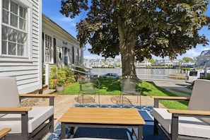 Un patio con tavolo e sedie, un albero e vista su un lago e degli edifici.