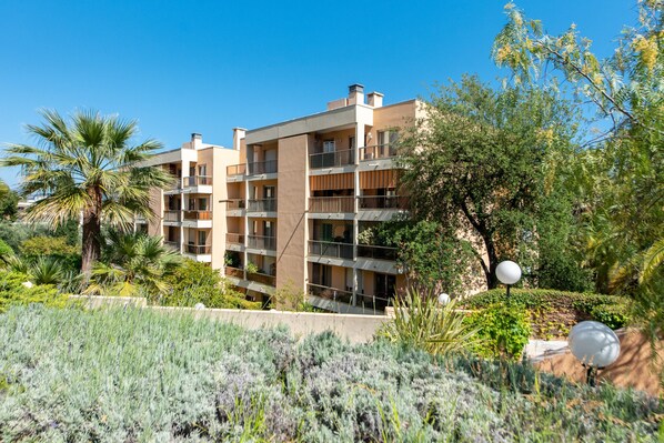 A multi-story hotel with balconies, surrounded by lush greenery and palm trees.