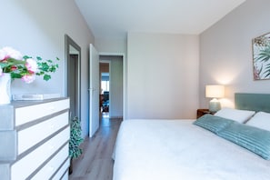 A bedroom with a bed, bedside table, lamp, and a wall-mounted artwork.
