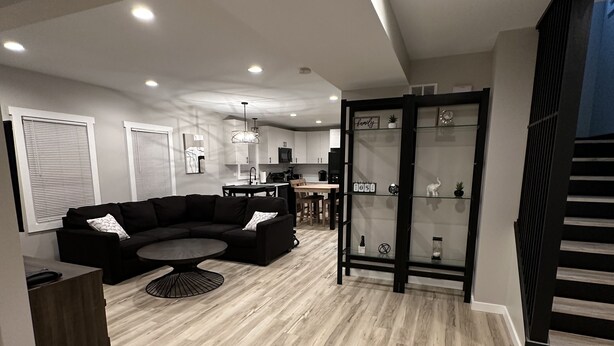 Una sala de estar moderna con un sofá modular, un comedor y una cocina al fondo.