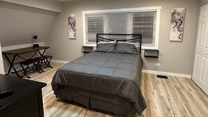 Un dormitorio con cama, escritorio y ventana con persianas.