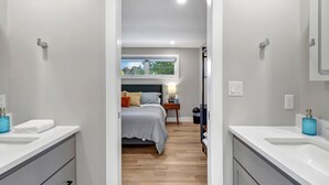 Une salle de bain moderne avec des accessoires blancs, un grand miroir et un distributeur de savon bleu.