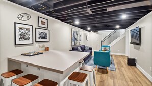 Un espace de vie moderne comprenant un îlot de cuisine, des tabourets de bar, un canapé et un escalier menant à un niveau supérieur.