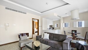 Una sala de estar moderna con un sofá gris, una mesa de centro de vidrio y un comedor con una mesa redonda y sillas.