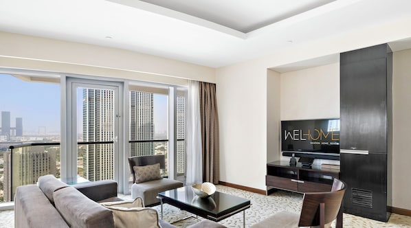 A modern living room with a sofa, armchair, and coffee table. A flat-screen TV is mounted on the wall.