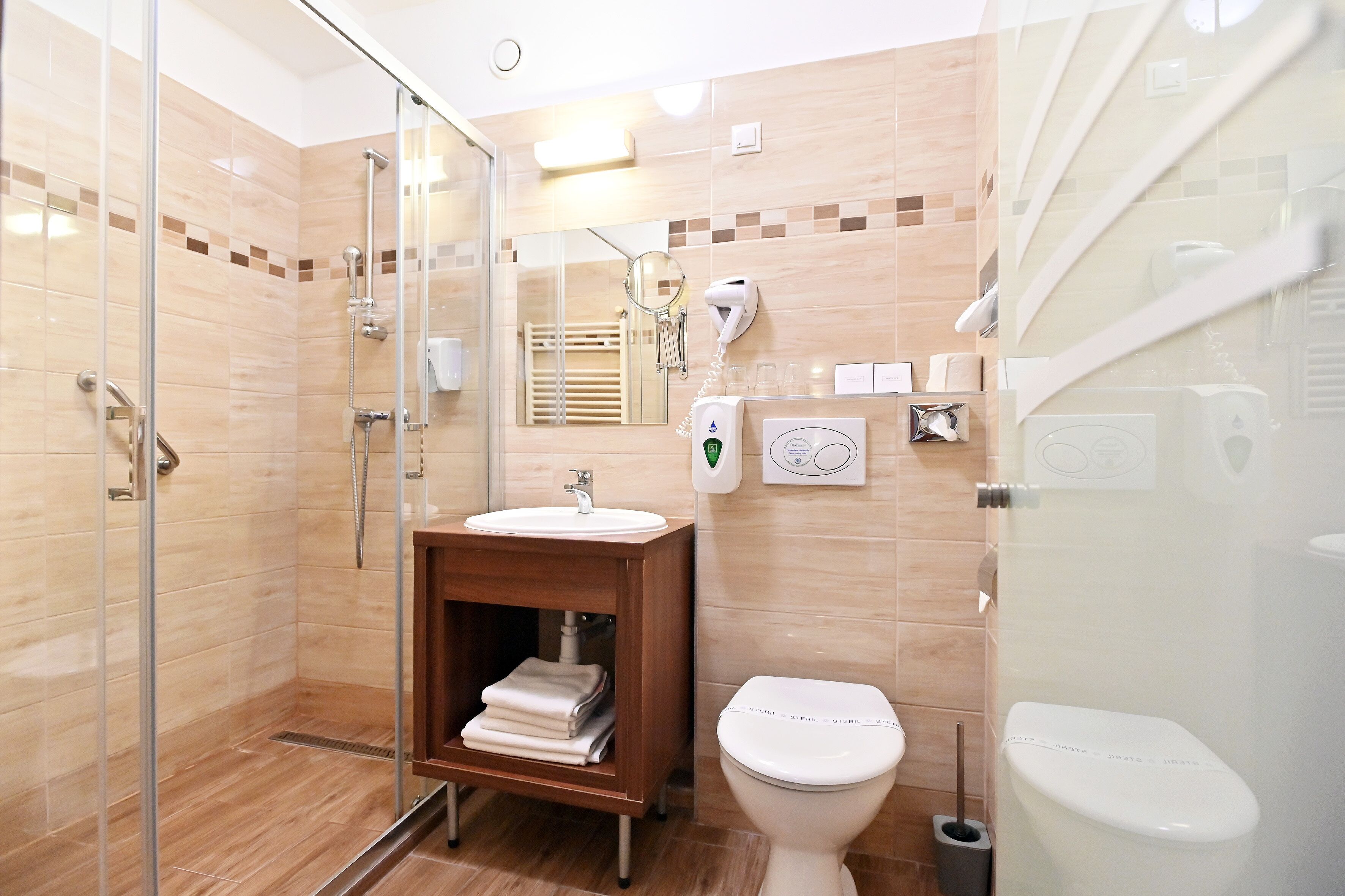 Un baño moderno con cabina de ducha de vidrio, tocador de madera con lavamanos y inodoro.