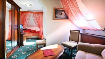 Ein Hotelzimmer mit einem Bett, einer Sitzecke inklusive Sessel, einem kleinen Tisch und einem großen Spiegel.
