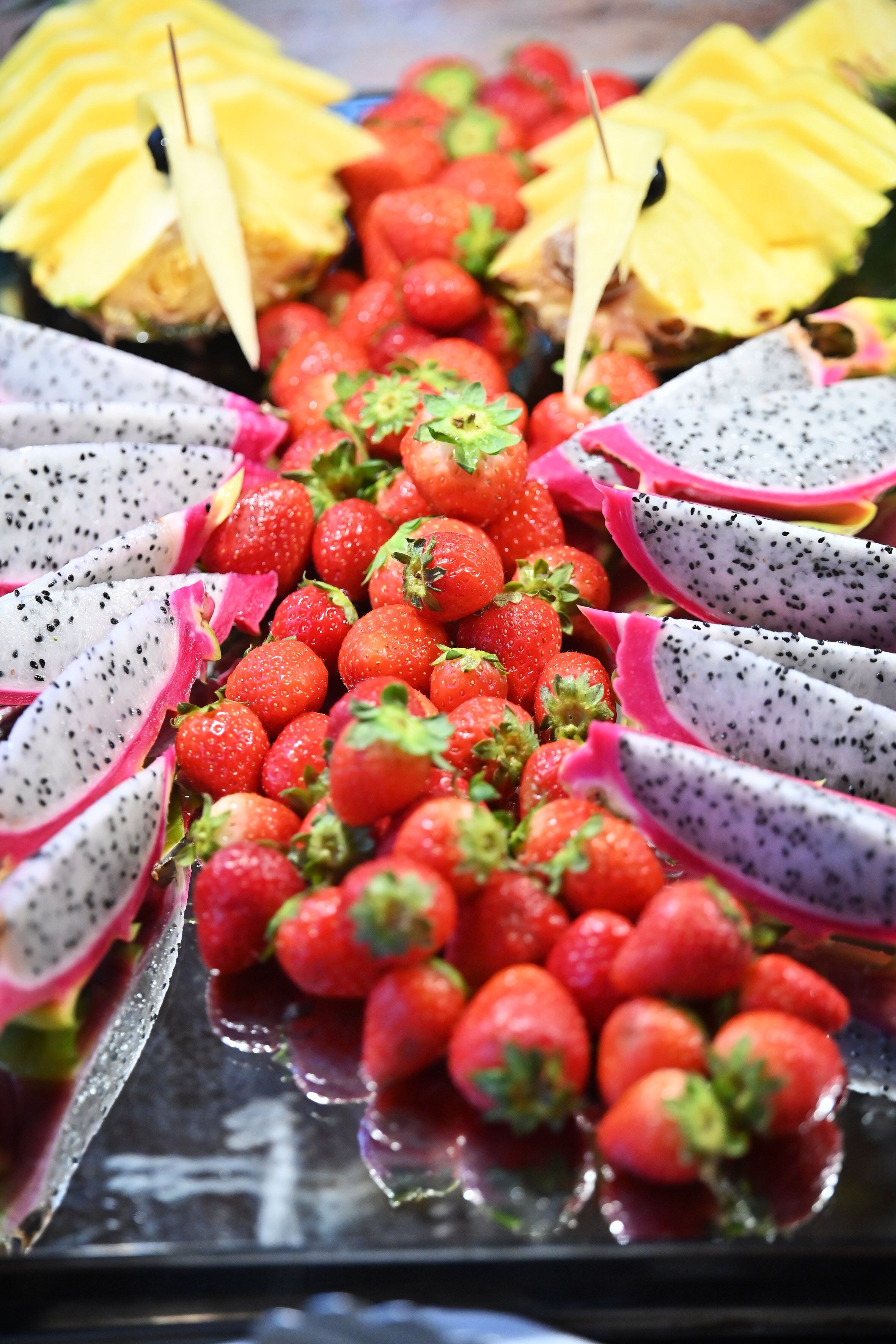 Una bandeja de frutas con fresas y rodajas de pitaya.