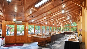 Una habitació àmplia amb una llarga taula de buffet, bigues de sostre de fusta i grans finestres.